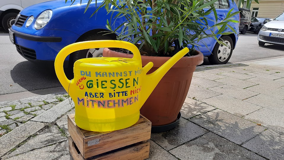 Ein Foto, dass eine gelbe Gießkanne zeigt, auf der geschrieben steht: "Du kannst mich gießen, aber bitte nicht mitnehmen!".